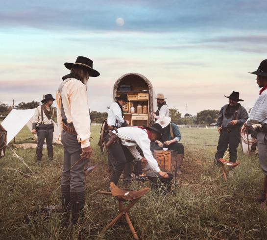 People in a field with a old wagon